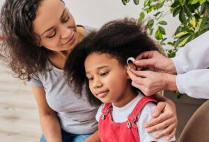 Parent and child wearing protective earmuffs while using hearing-safe practices outdoors.