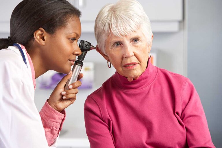 Adult and older adult speaking face to face in a quiet, well-lit room with an audiogram on a table.